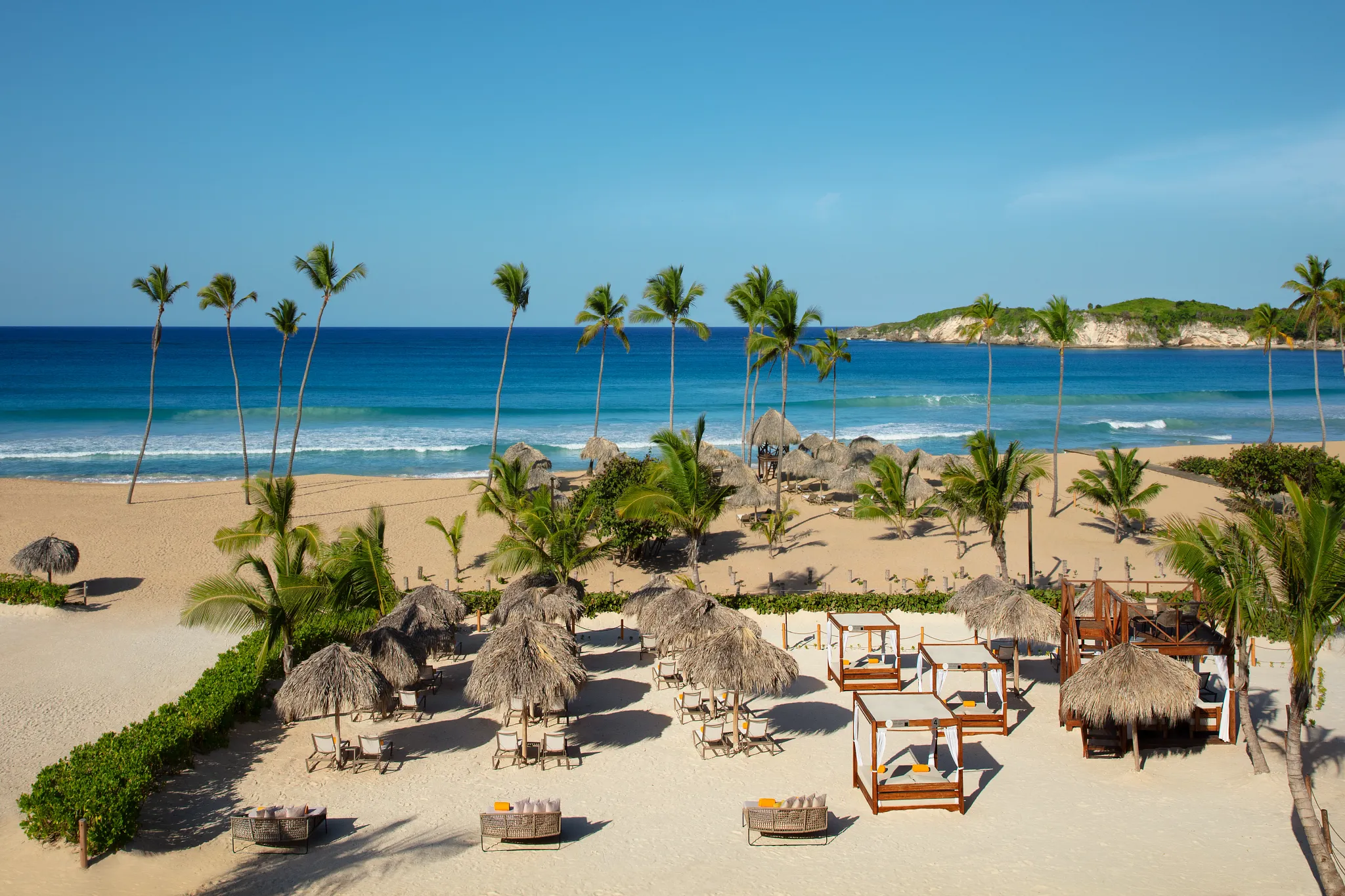 Beachfront cabanas and palm trees along Macao Beach at Dreams Macao Beach Punta Cana Resort.